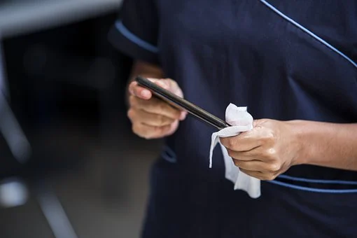 Man using a disinfectant wipe to sanitize his smartphone